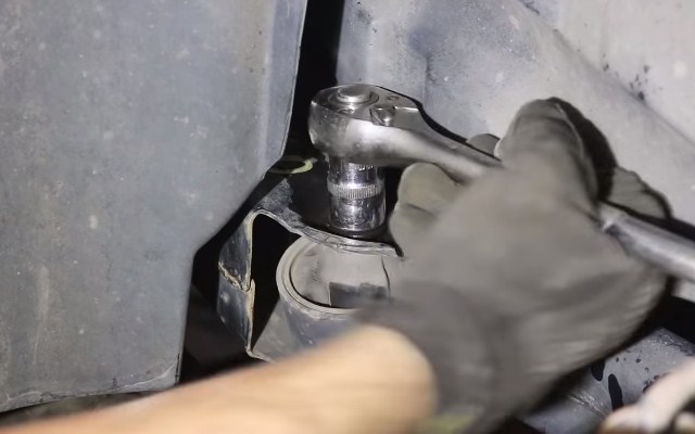 Откручивание болта переднего кронштейна крепления